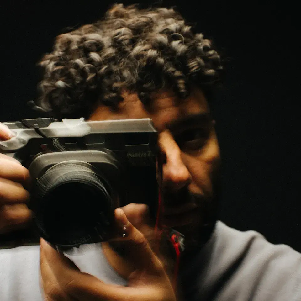 Man die door zijn spiegelreflex camera kijkt, © Jari Nuno